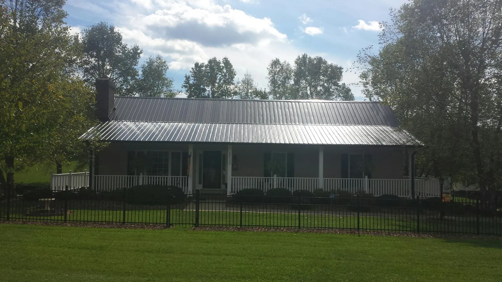 Gray metal roof on a brick ranch with a full width front porch in Luther