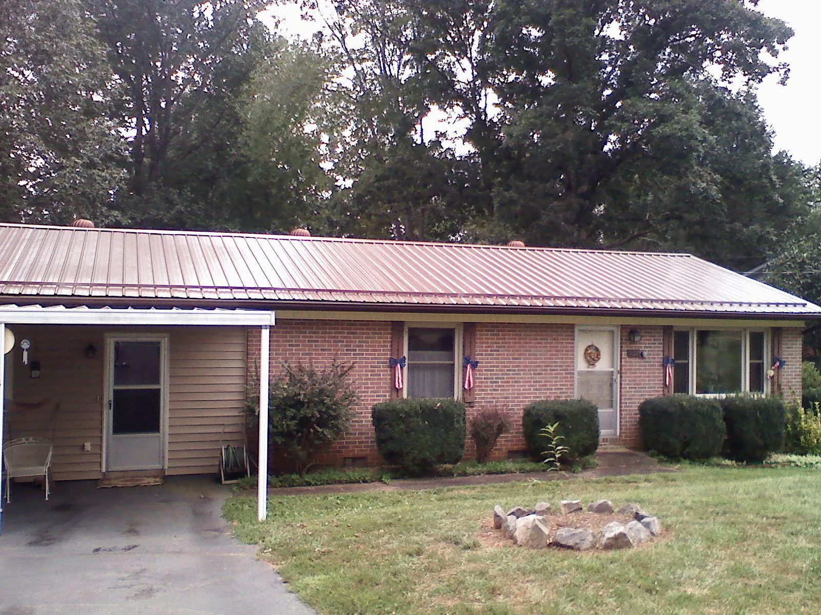 Bronze metal roof and carport on a brick ranch home — Roof Repair work by our crew in Luther