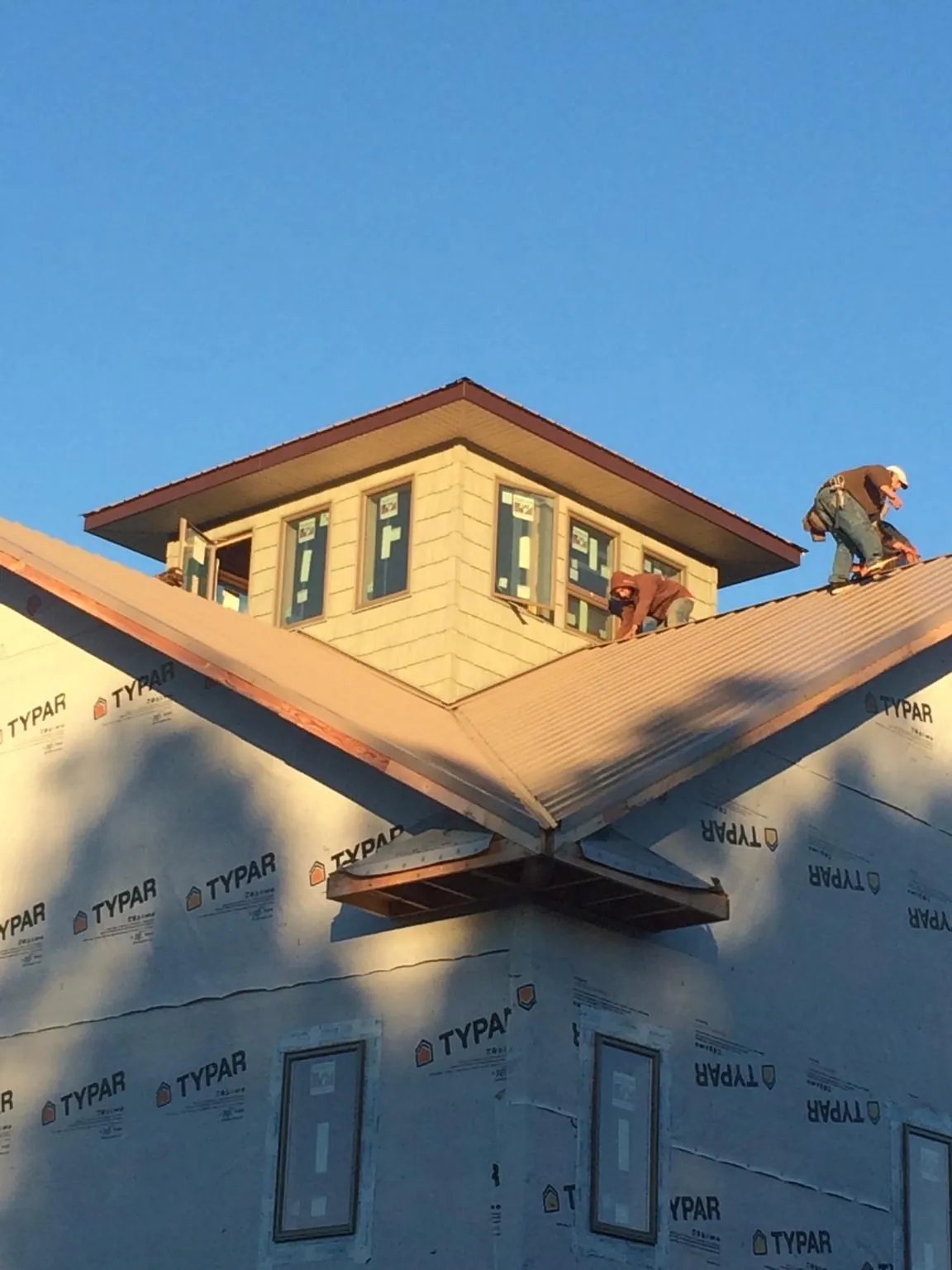 Roofers working around a rooftop cupola on a new metal roof at sunset — Roof Waterproofing in Luther by Roofing Brothers